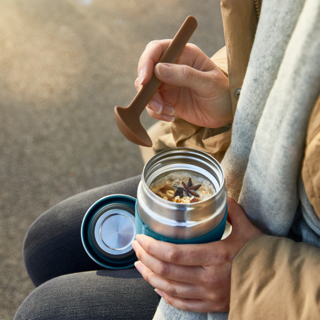 Black+Blum food flask with a branded spoon that comes with it on a park bench on a crisp springs morning.