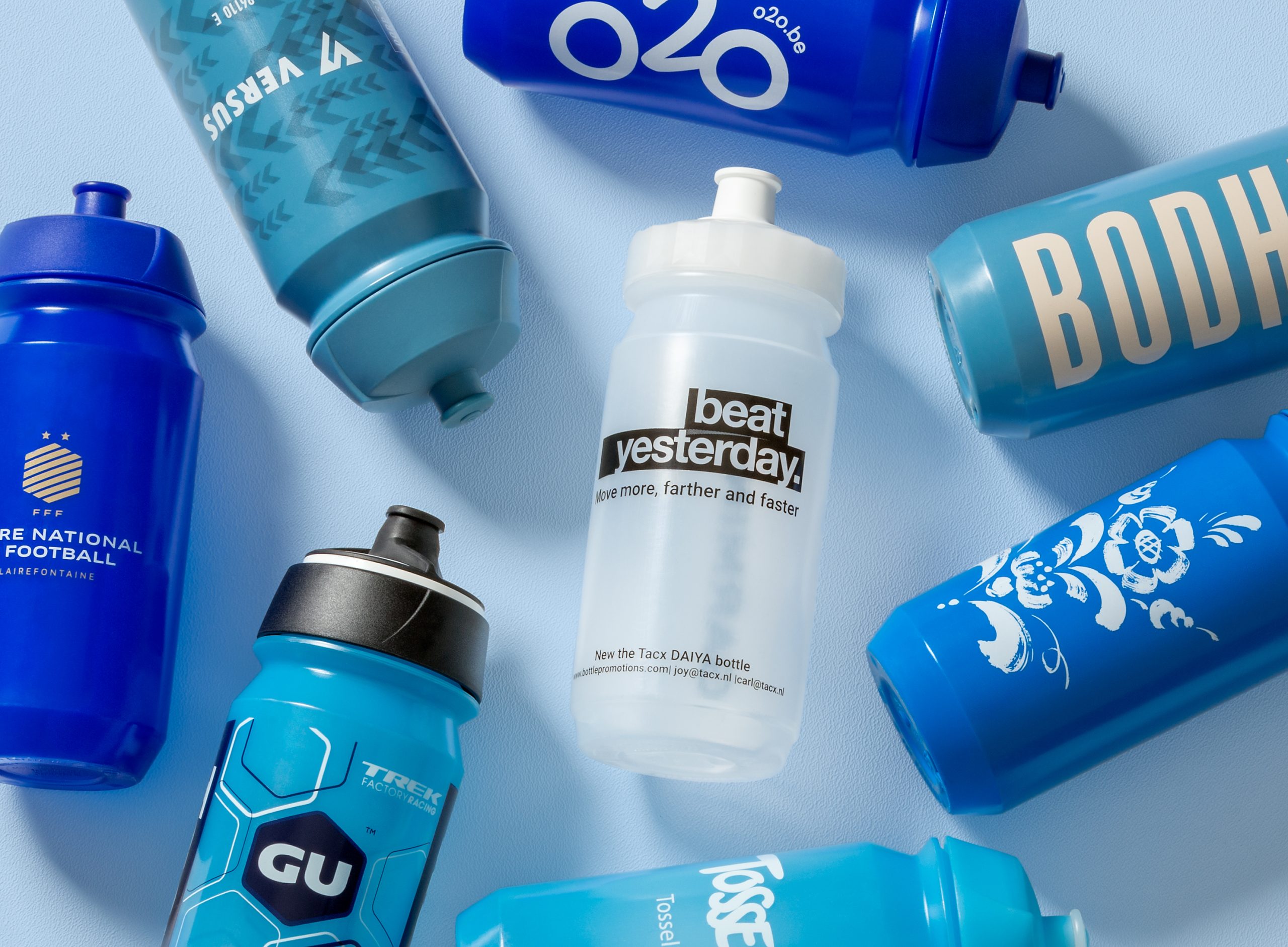 An array of customised sports bottles laid out across a bright blue background.