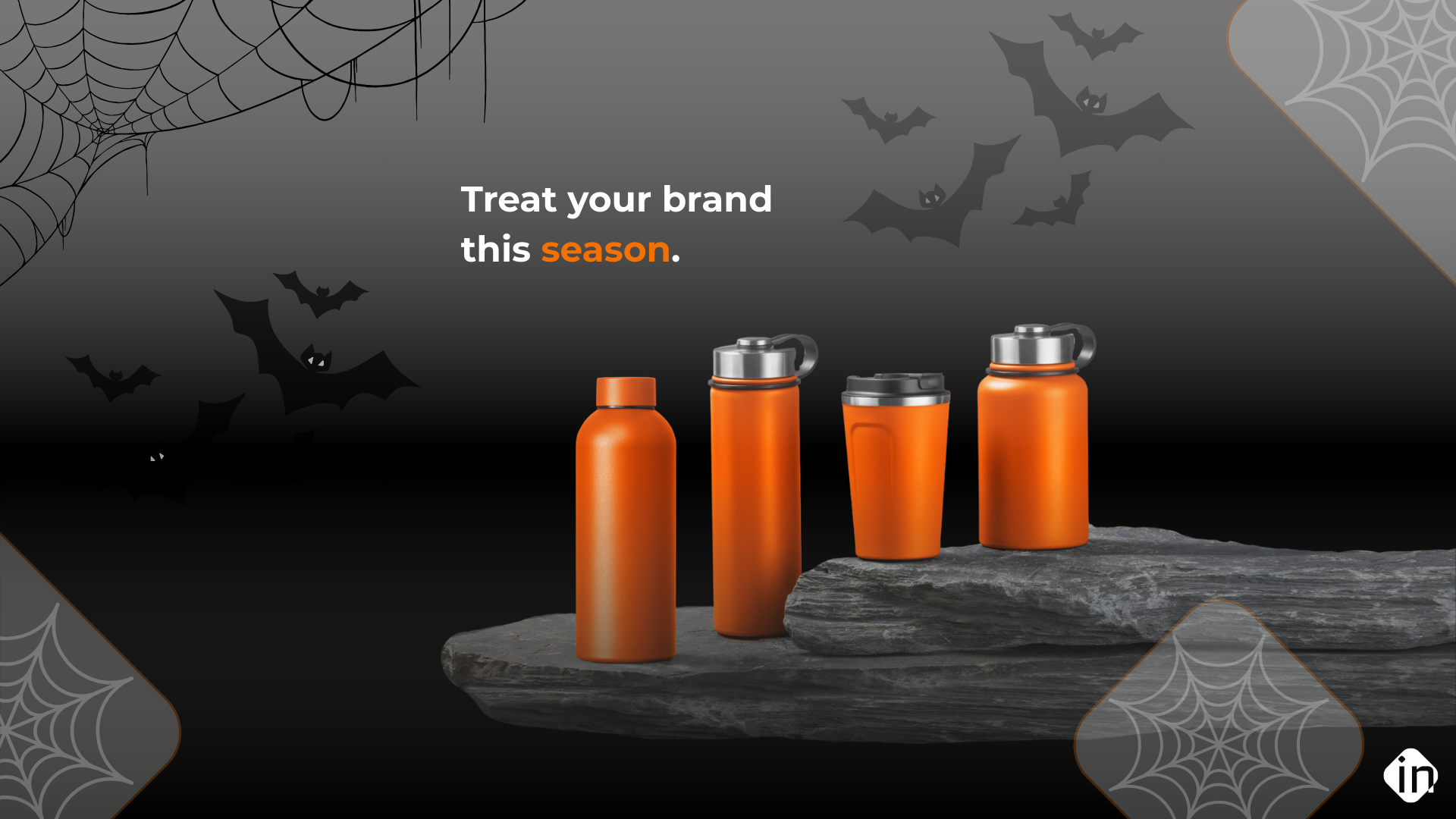 Halloween-themed promotional image featuring orange branded drinkware bottles and tumblers displayed on stone with bats and spider webs in the background.