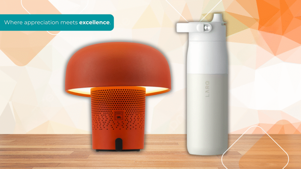 Premium branded corporate gifts including a modern orange JBL desk lamp and a sleek white LARQ bottle displayed on a wooden surface with the tagline “Where appreciation meets excellence.”