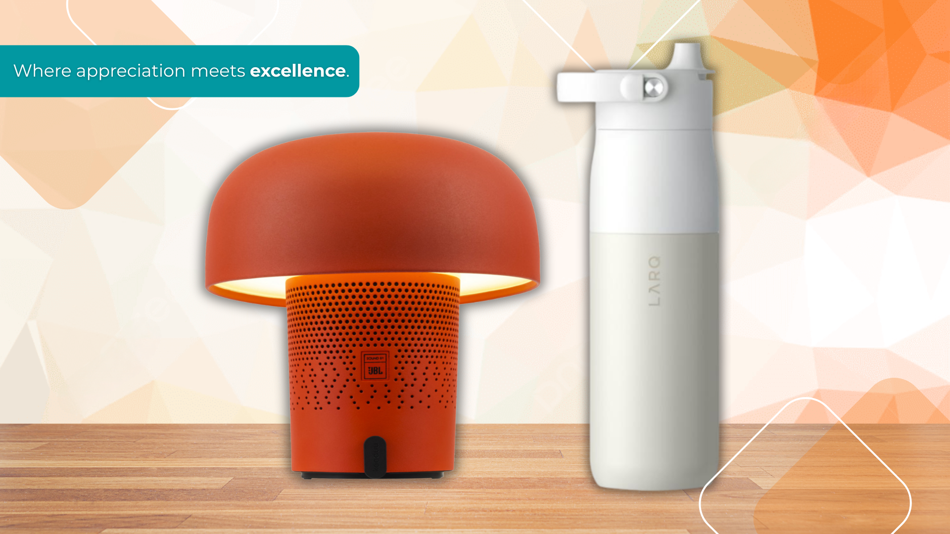Premium branded corporate gifts including a modern orange JBL desk lamp and a sleek white LARQ bottle displayed on a wooden surface with the tagline “Where appreciation meets excellence.”